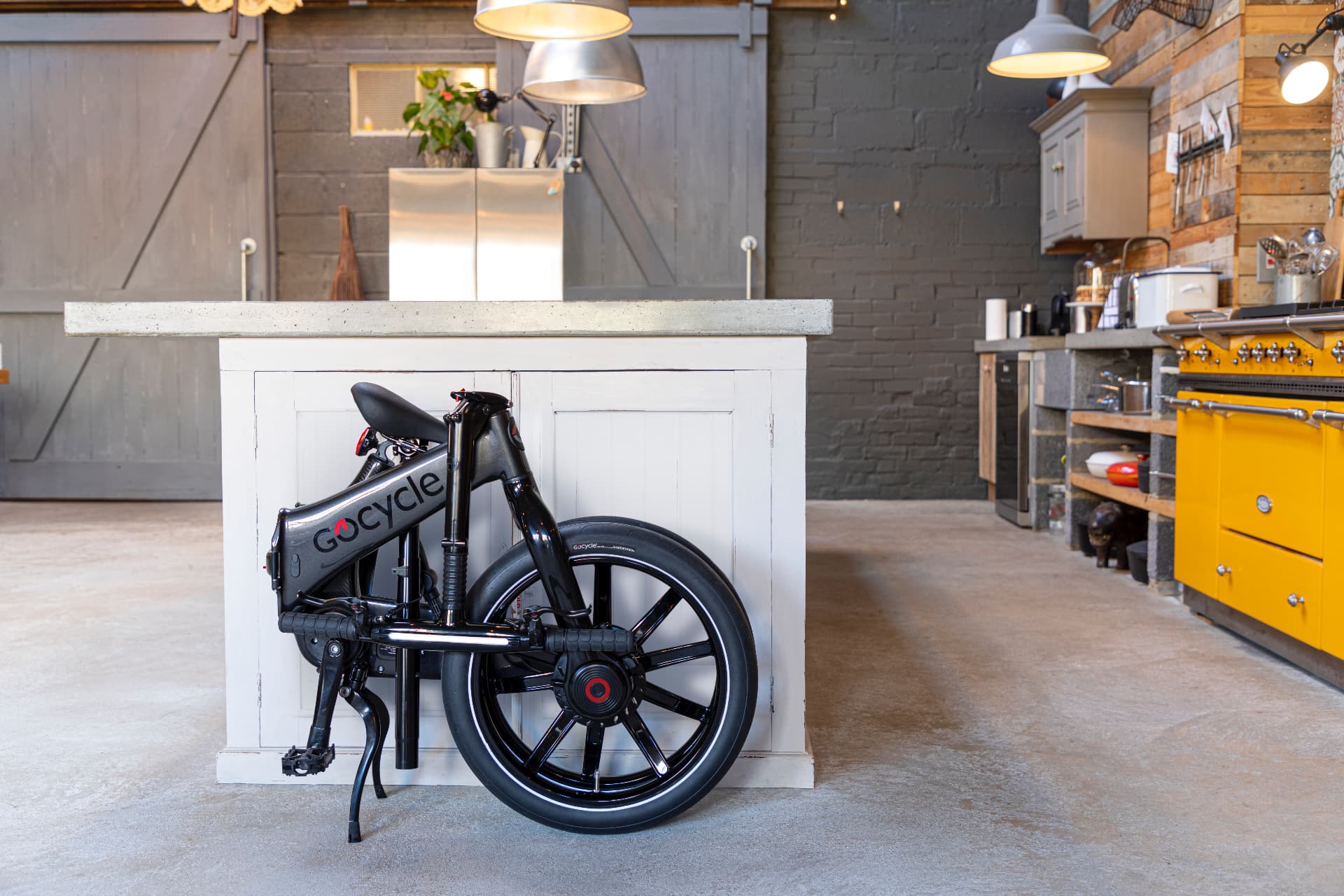 Vélo électrique pliant Gocycle G4i gris plié, rangé dans une cuisine
