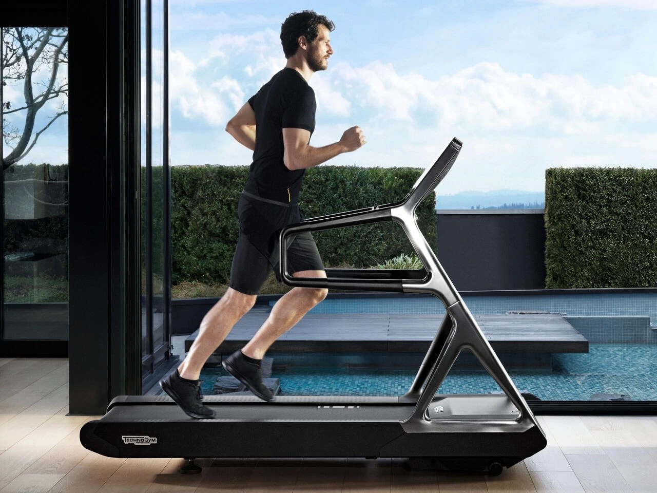 Technogym Run Personal — tapis de course premium face à la piscine, en plein air
