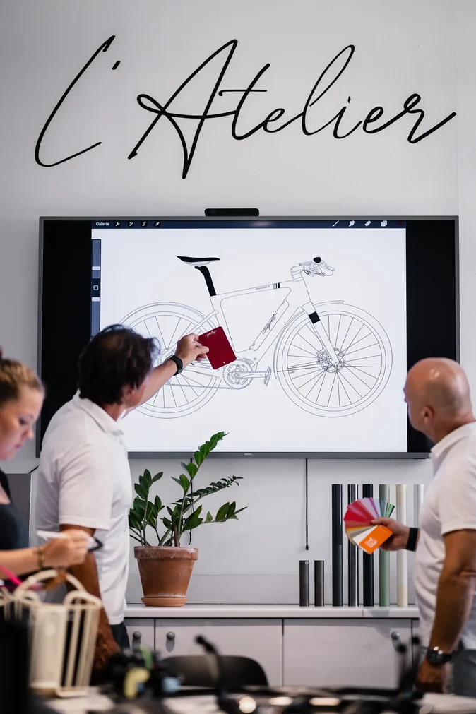 Atelier Stajvelo : l'équipe compare des nuanciers de teintes devant le croquis d'un vélo électrique